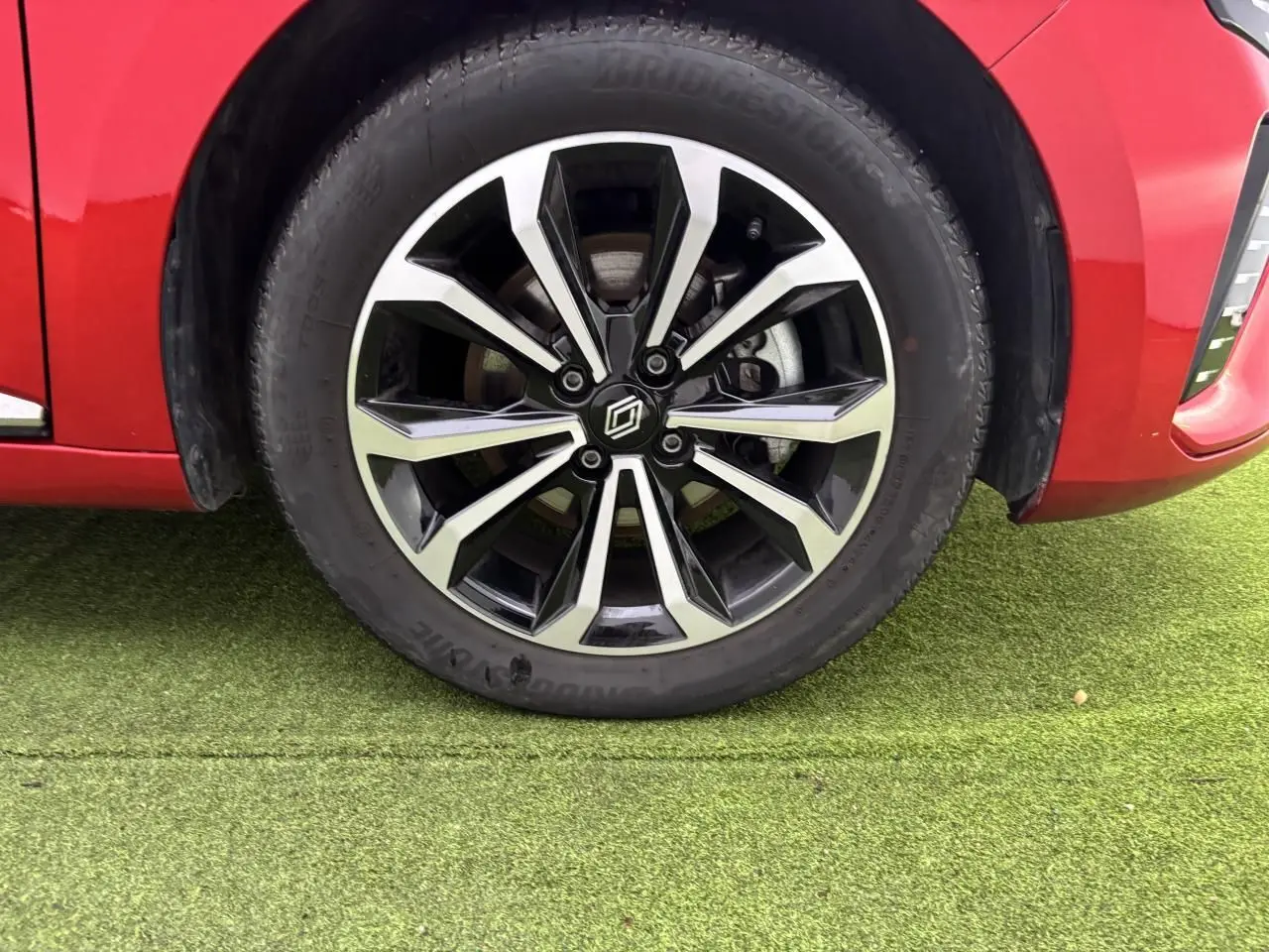 Gros plan sur la roue avant gauche avec jante alliage noire et argentée de la Renault Clio rouge flamme.