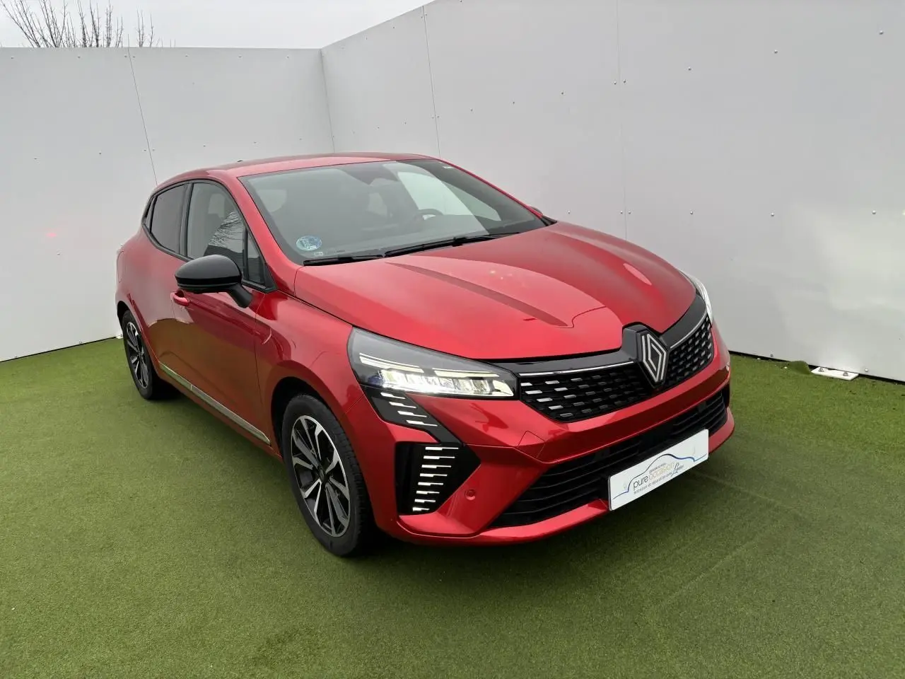 Renault Clio V hybride rouge flamme métal vue 3/4 avant droit avec phares LED et jantes alliage 16 pouces.