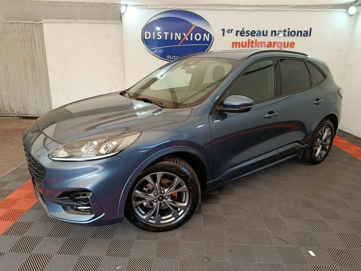 Vue 3/4 avant d'un Ford Kuga bleu 2024 finition St Line avec jantes alliage et vitres teintées en showroom.