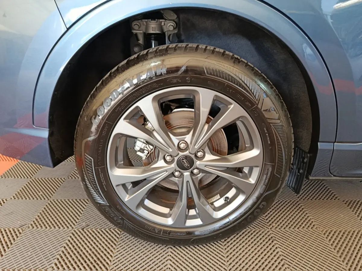 Gros plan sur la roue avant droite du Ford Kuga bleu 2024 avec jante alliage et pneu Goodyear visible.