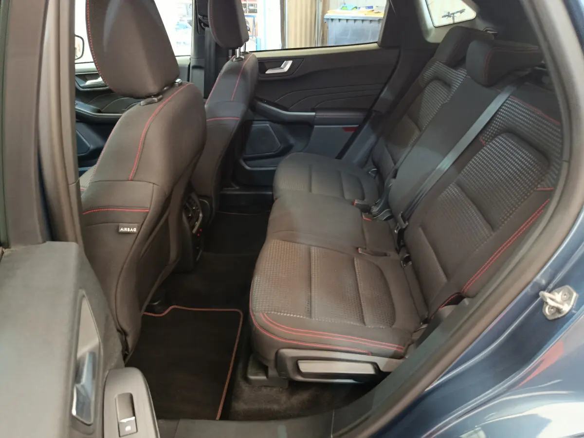 Vue côté gauche des sièges arrière noirs avec surpiqûres rouges du Ford Kuga 2024 bleu, finition St Line