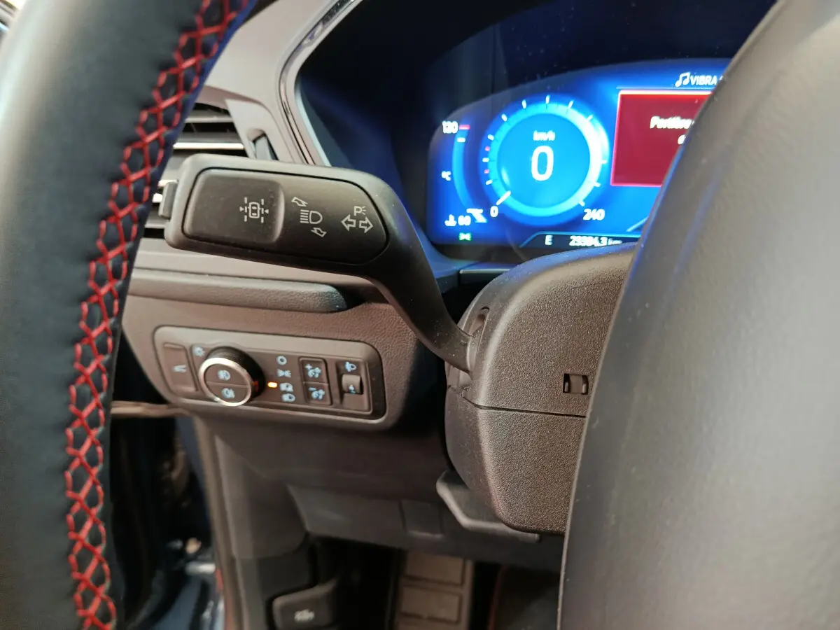 Gros plan sur la manette de clignotant et le tableau de bord numérique bleu du Ford Kuga 2024 St Line.