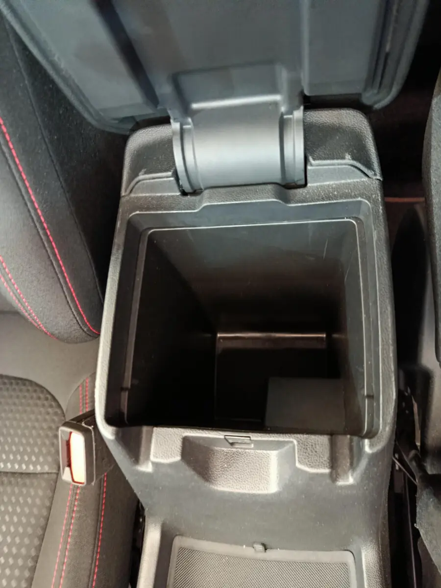 Vue plongeante sur la console centrale ouverte du Ford Kuga 2024 bleu, avec surpiqûres rouges sur siège noir.