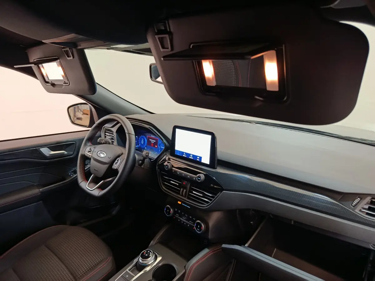 Vue intérieure côté conducteur du Ford Kuga bleu 2024, tableau de bord moderne avec écran tactile et volant cuir.