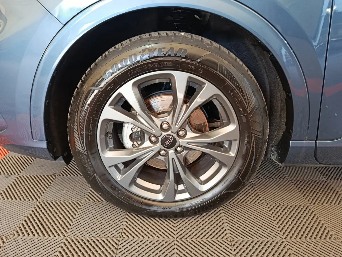 Gros plan sur la roue avant droite du Ford Kuga bleu 2024, mettant en valeur la jante alliage et le pneu Goodyear.