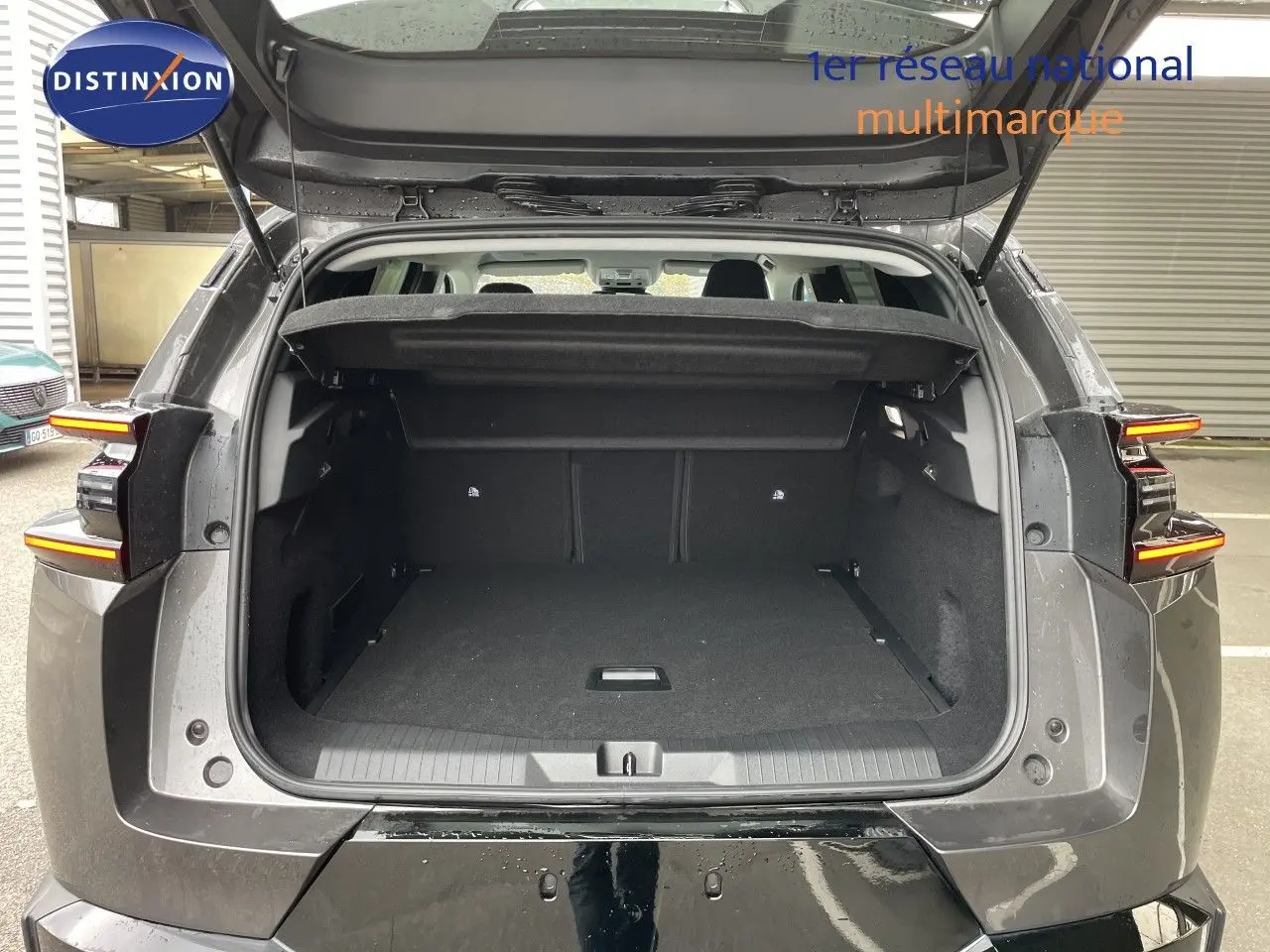 Coffre ouvert en vue arrière d’un Citroën C5 Aircross Hybrid gris platinium métal, avec feux arrière allumés.