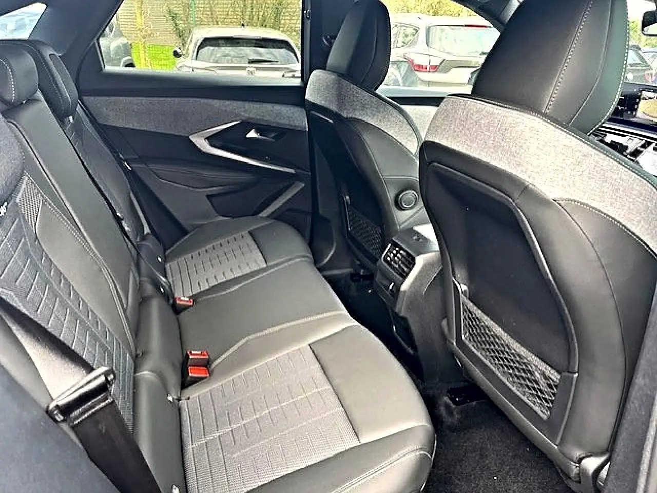 Vue intérieure arrière du Peugeot 3008 2025 gris Artense, montrant la banquette et les dossiers avant en cuir et tissu.