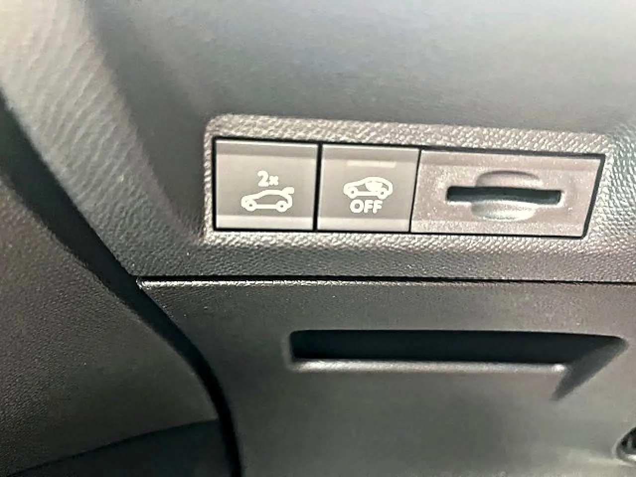 Gros plan sur les commandes d'ouverture du coffre et de désactivation de l'assistance au freinage dans un Peugeot 3008 gris Artense.