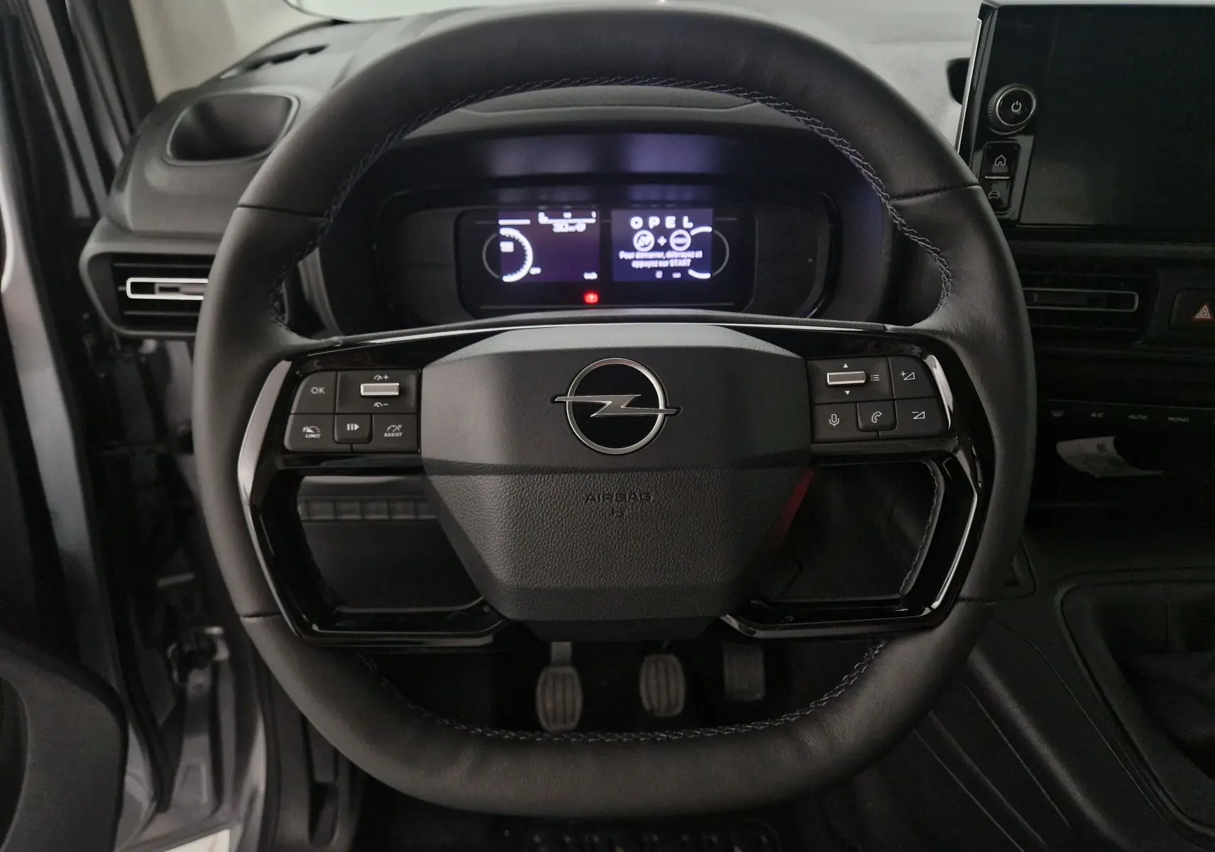 Vue rapprochée du volant en cuir noir de l'Opel Combo Life gris Artense avec tableau de bord digital allumé.