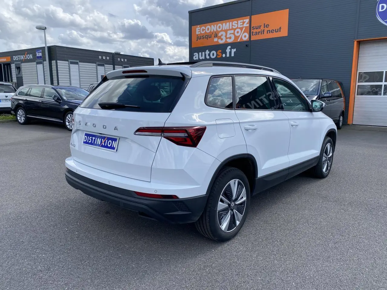Vue 3/4 arrière droite d'un Skoda Karoq blanc Moon métallisé avec jantes alliage et toit ouvrant panoramique.