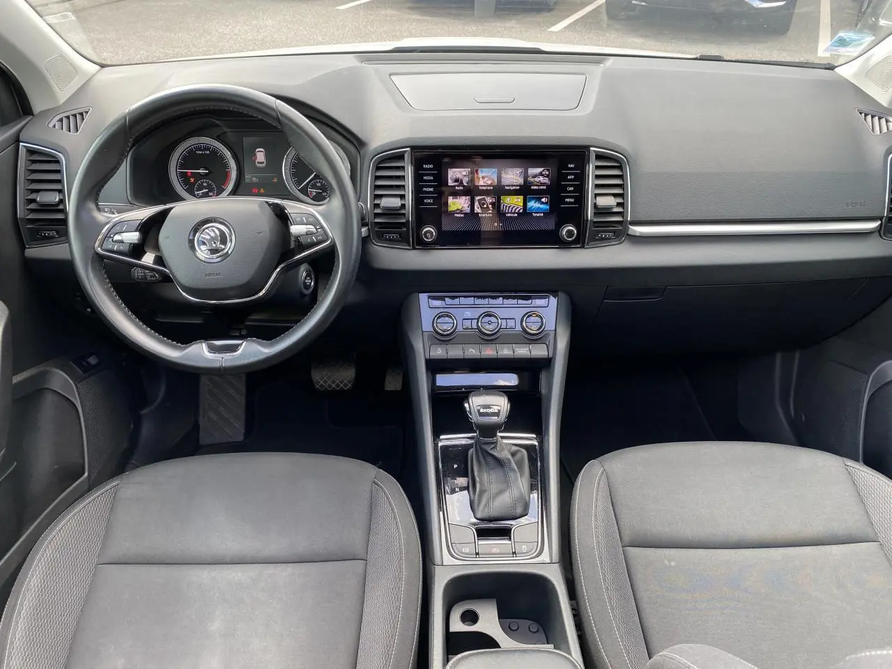 Vue intérieure avant du Skoda Karoq 2022 avec tableau de bord noir, écran tactile et levier de vitesse DSG7.