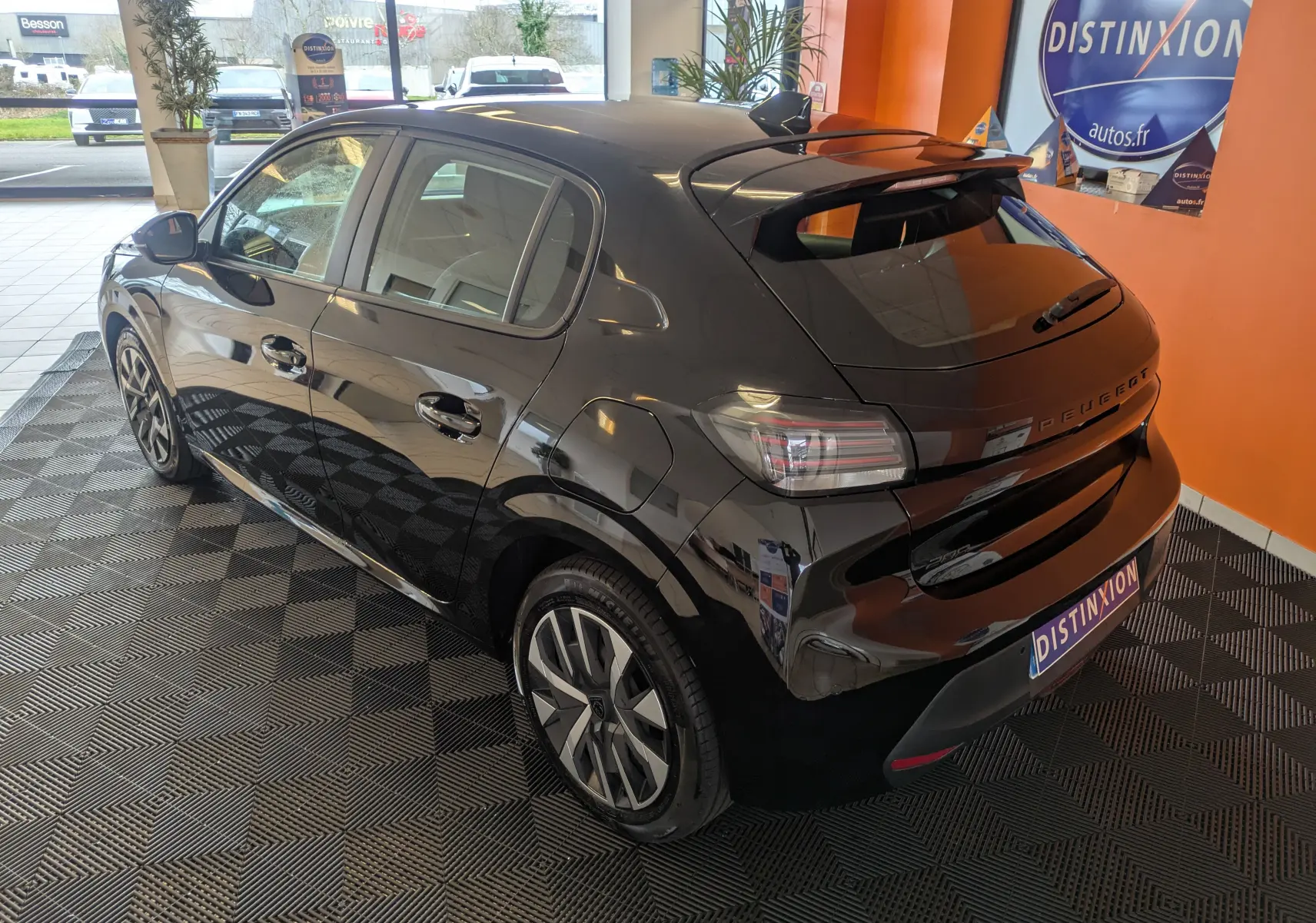 Vue 3/4 arrière droite d'une Peugeot 208 noire Perla 2024 avec jantes alliage et toit avec aileron.
