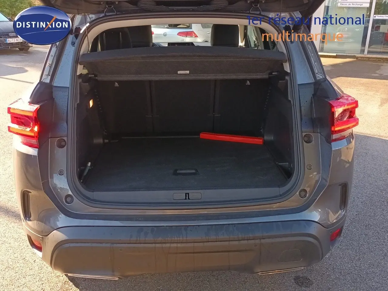 Coffre ouvert vu de l'arrière d'un Citroën C5 Aircross gris platinium métal avec feu arrière allumé.