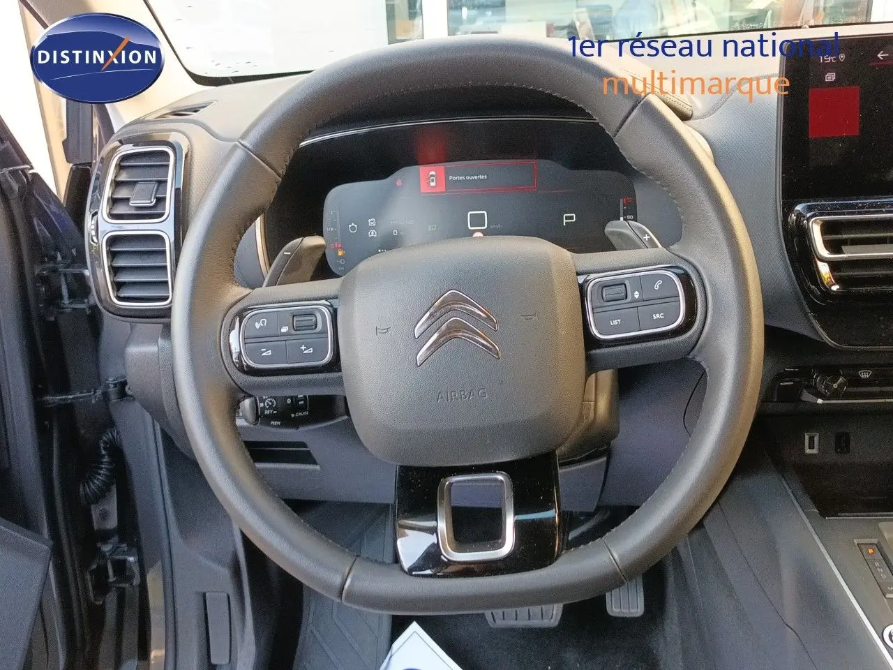 Vue centrée sur le volant cuir noir du Citroën C5 Aircross 2025, avec tableau de bord digital et commandes intégrées.