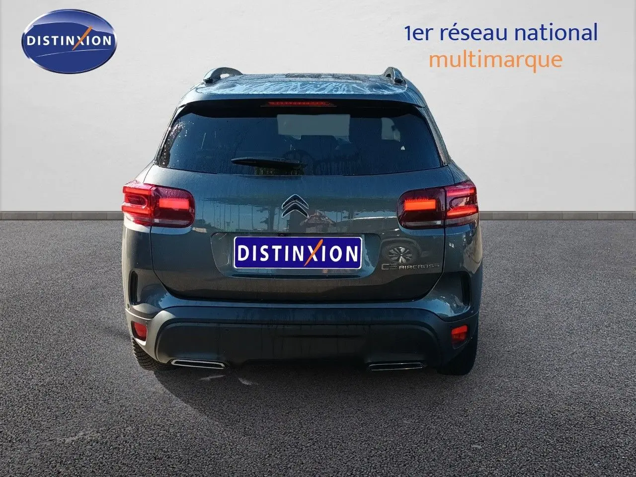 Vue arrière d'un Citroën C5 Aircross gris platinium métal 2025 avec feux arrière allumés et double sortie d'échappement.