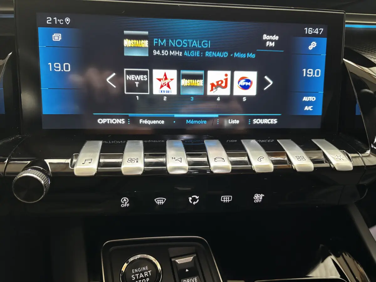 Vue rapprochée de la console centrale tactile du Peugeot 508 gris foncé, affichant radio FM et commandes piano.