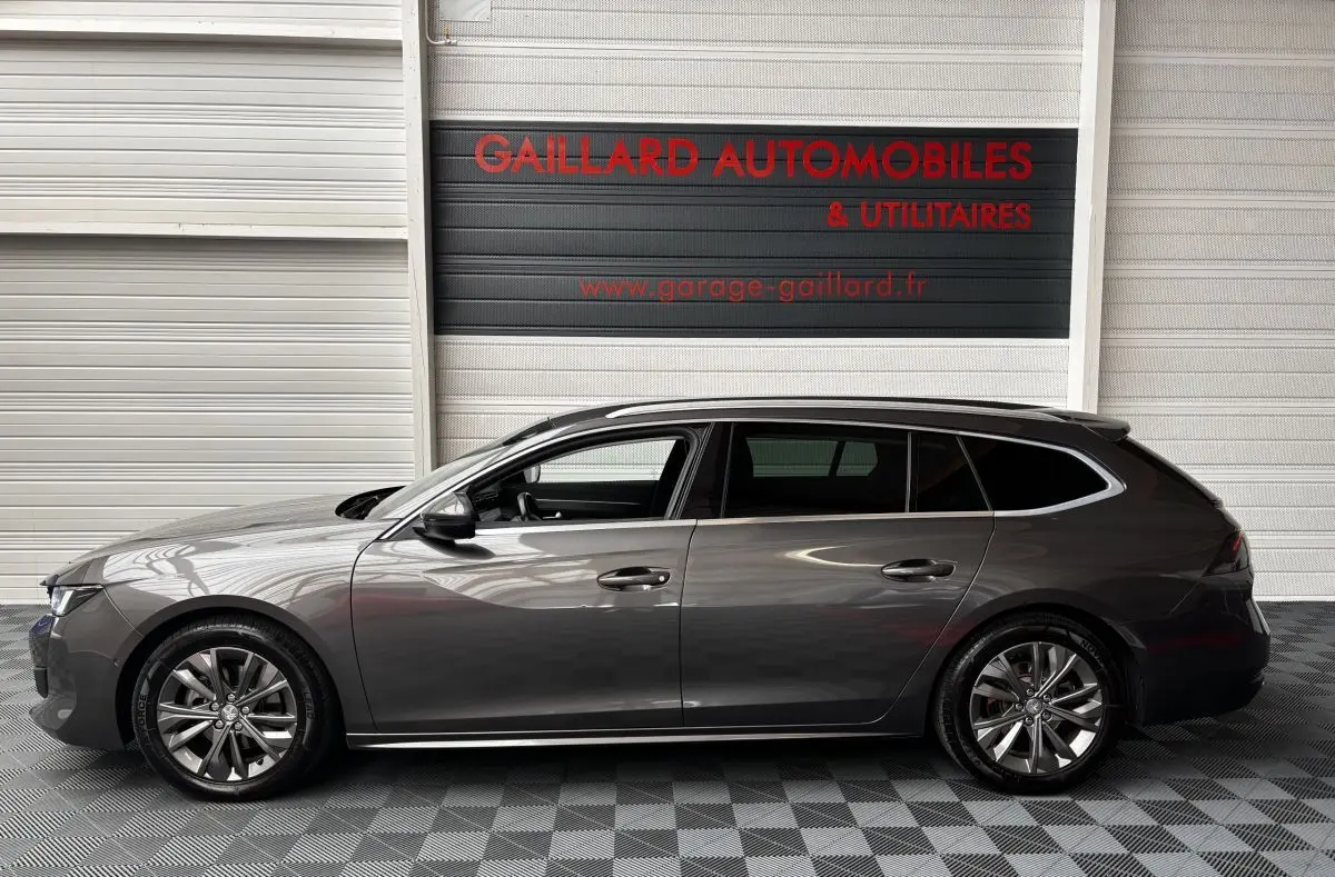 Profil côté gauche d'une Peugeot 508 break gris foncé 2019 garée en intérieur avec jantes alliage et vitres teintées.