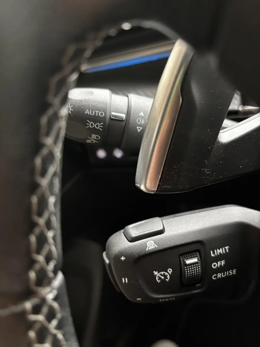 Gros plan sur commandes au volant noir et gris de la Peugeot 508 BlueHDi 2019, avec réglages croisière et phares automatiques.