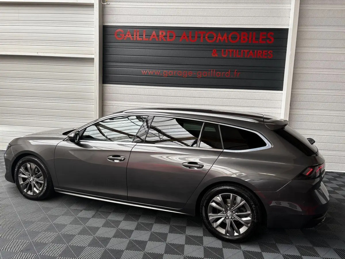 Peugeot 508 break gris foncé vue de profil côté gauche dans un showroom avec sol damier noir et gris.
