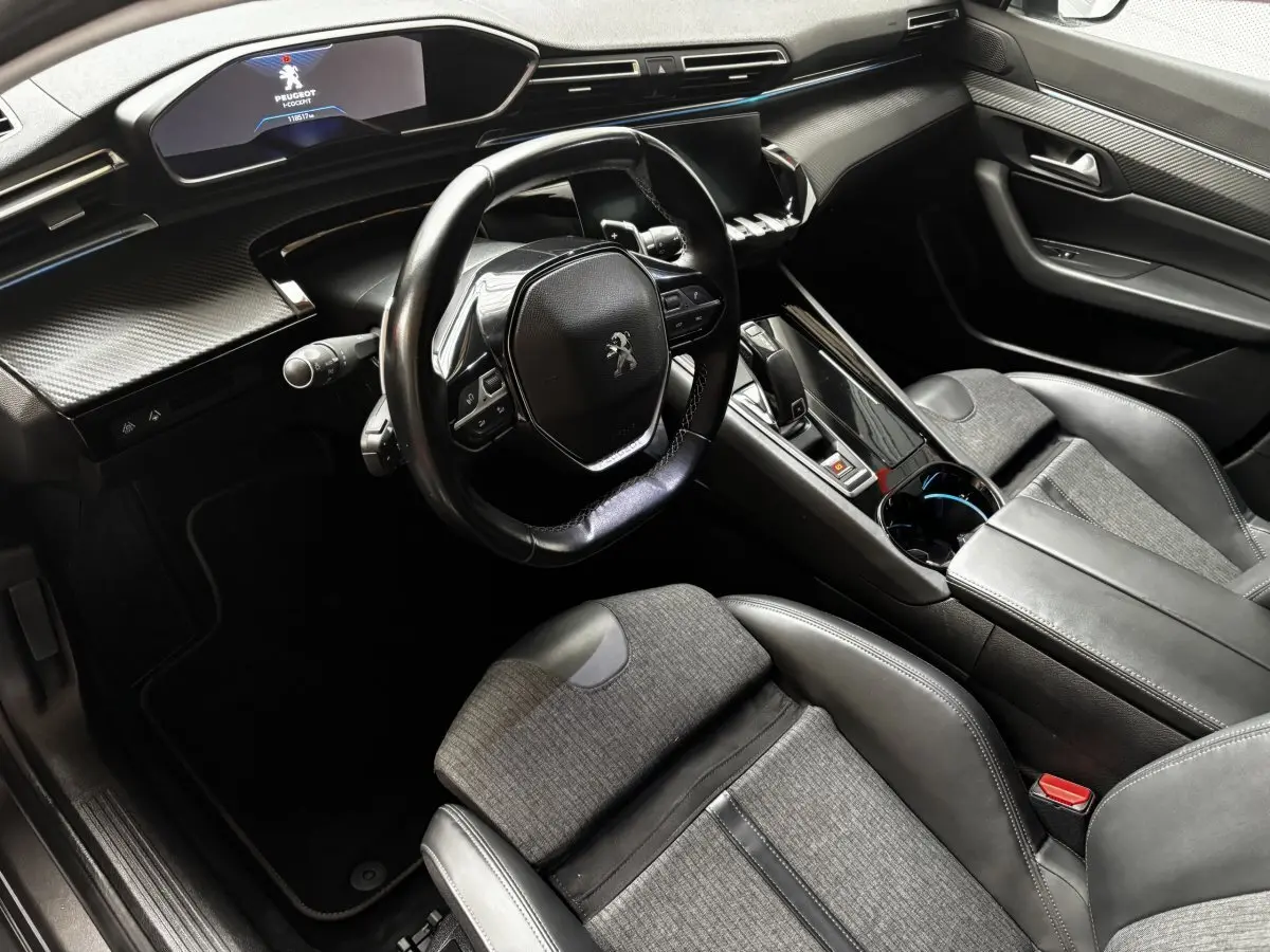 Intérieur de Peugeot 508 gris foncé vu côté conducteur, volant compact et tableau de bord numérique lumineux.