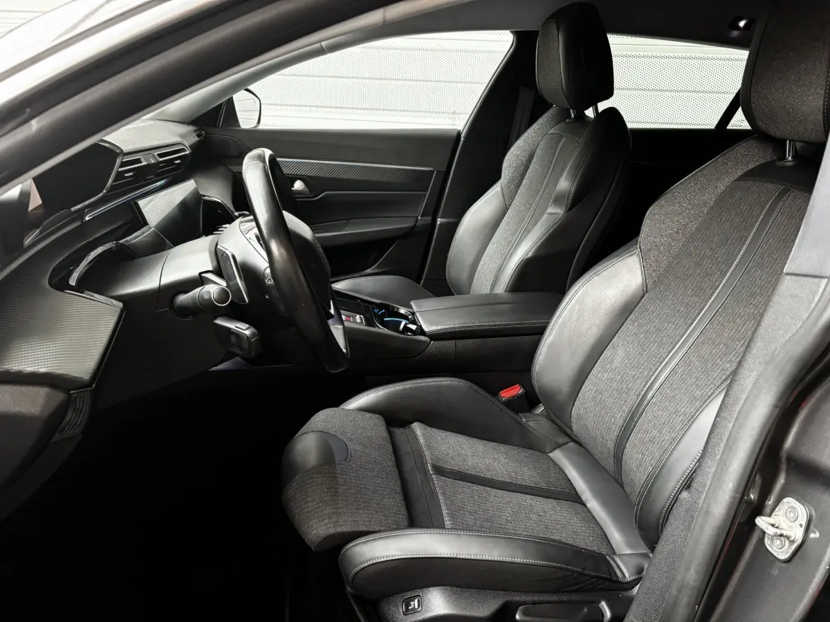 Intérieur de la Peugeot 508 2019, vue côté conducteur, sièges tissu et cuir gris, tableau de bord moderne noir mat.