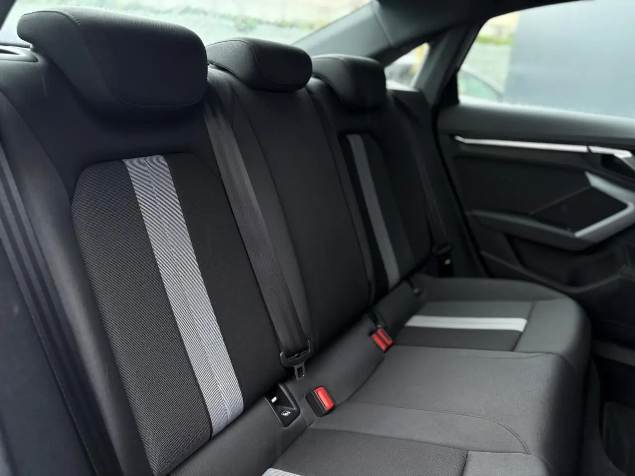 Vue latérale droite des sièges arrière noirs avec bandes grises de l'Audi A3 Berline 30 TFSI 116 S-tronic Advanced Edition 2024.