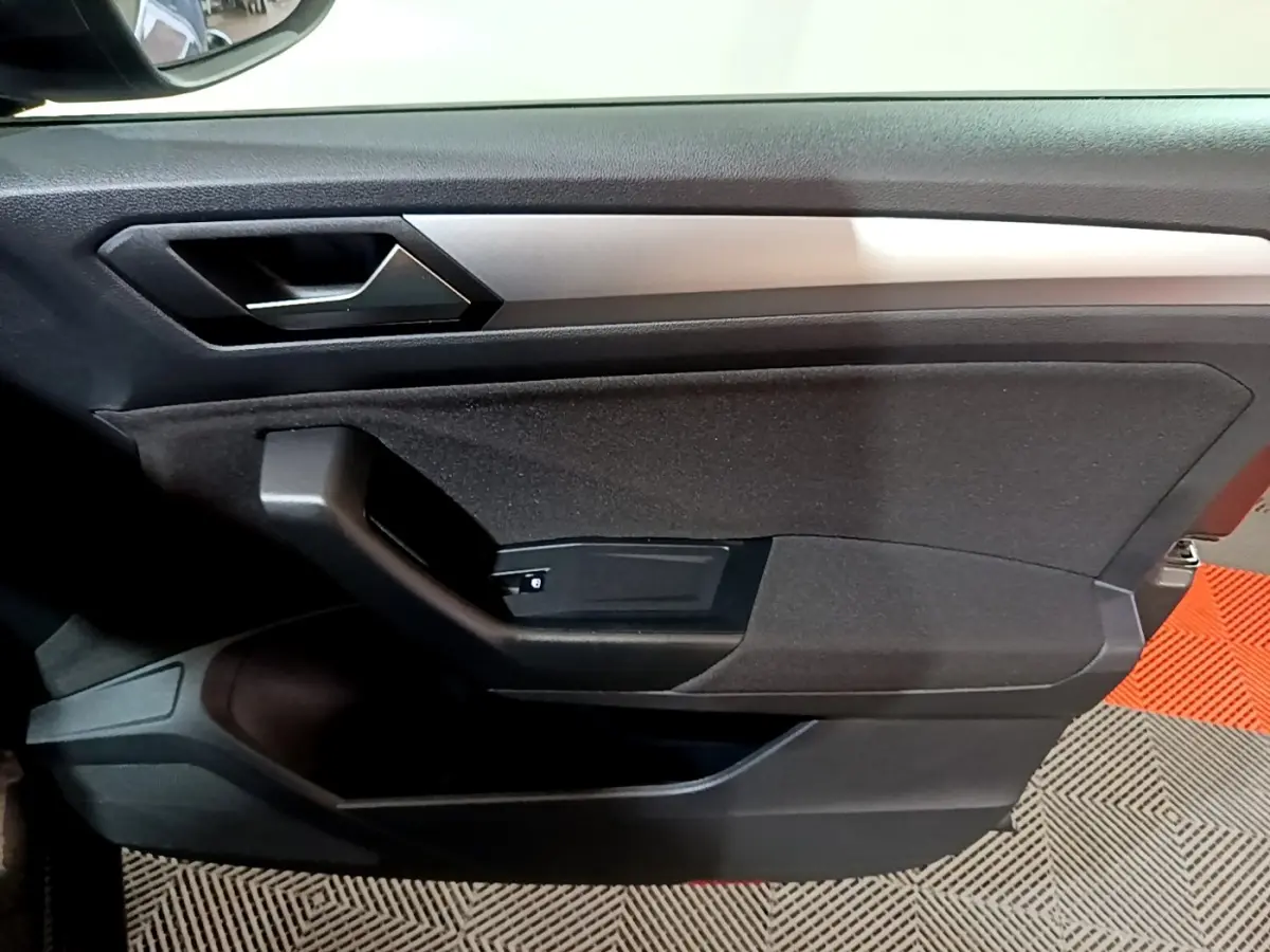 Détail de la porte intérieure côté conducteur du Volkswagen T-Roc gris foncé, avec poignée et insert argenté.