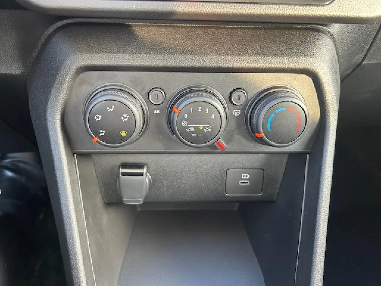 Gros plan sur les commandes de climatisation et prises USB du tableau de bord de la Dacia Sandero Stepway blanche.