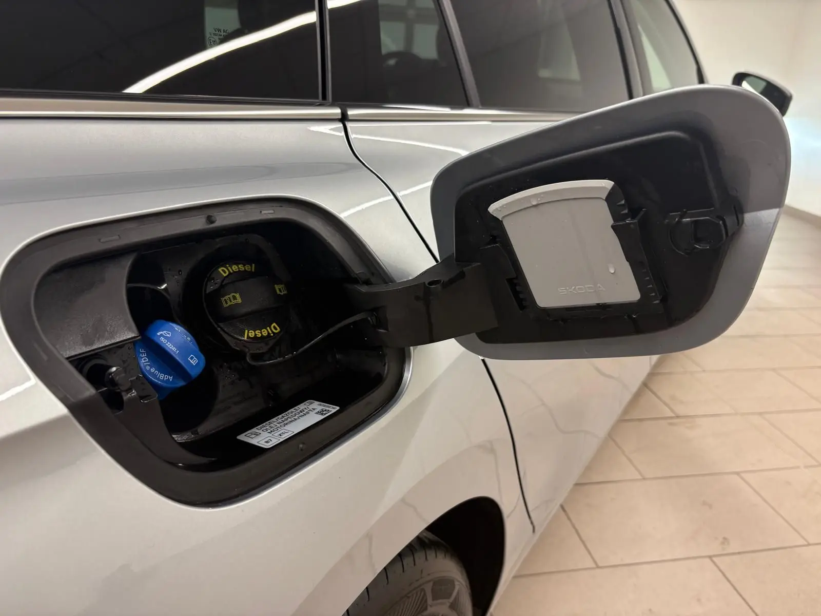 Bouchon de réservoir diesel ouvert côté gauche d’un Skoda Superb Combi gris argent 2025, avec bouchon AdBlue visible.