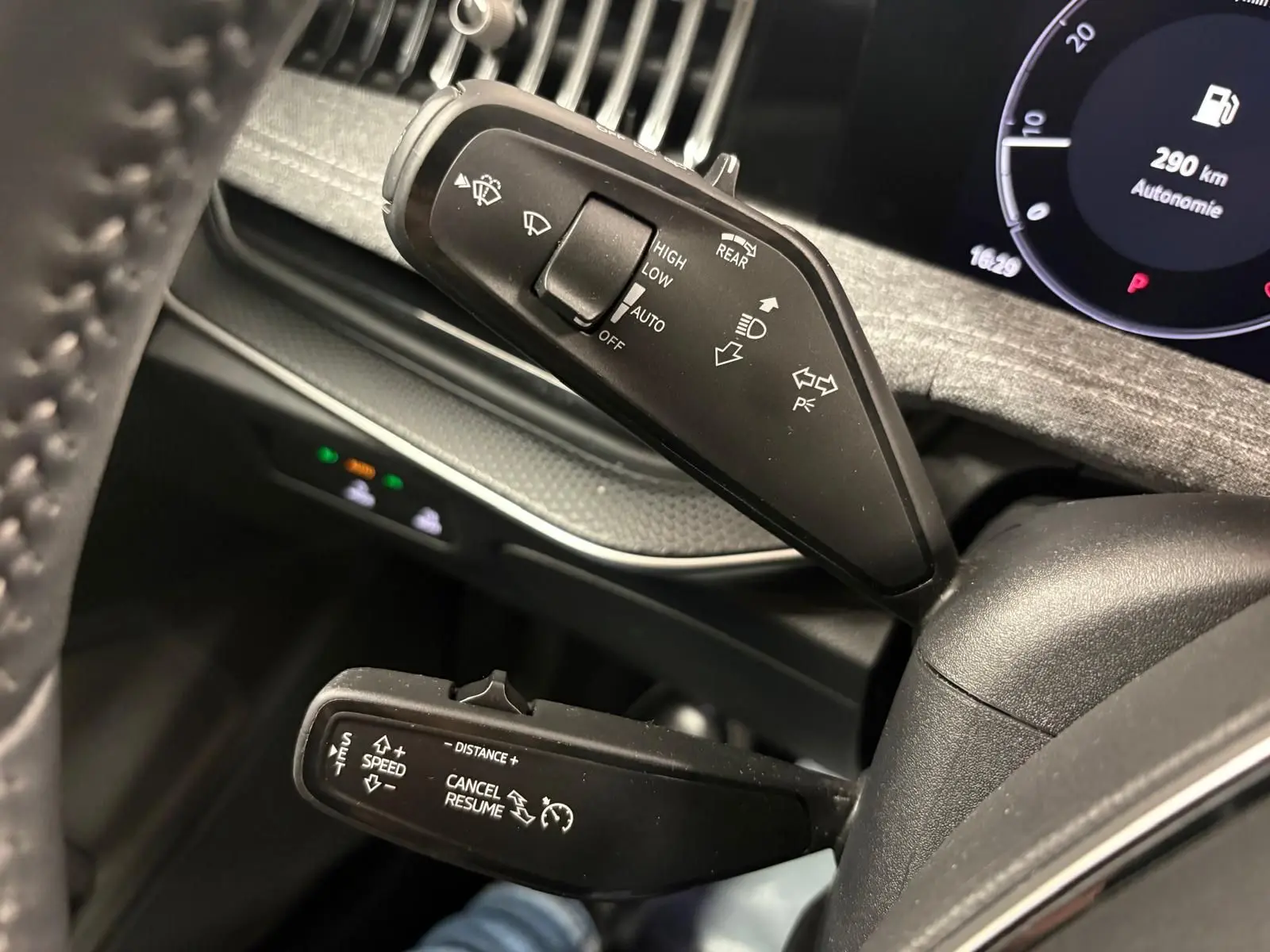 Détail intérieur du volant côté gauche du Skoda Superb Combi gris argent 2025, avec commandes de feux et régulateur.