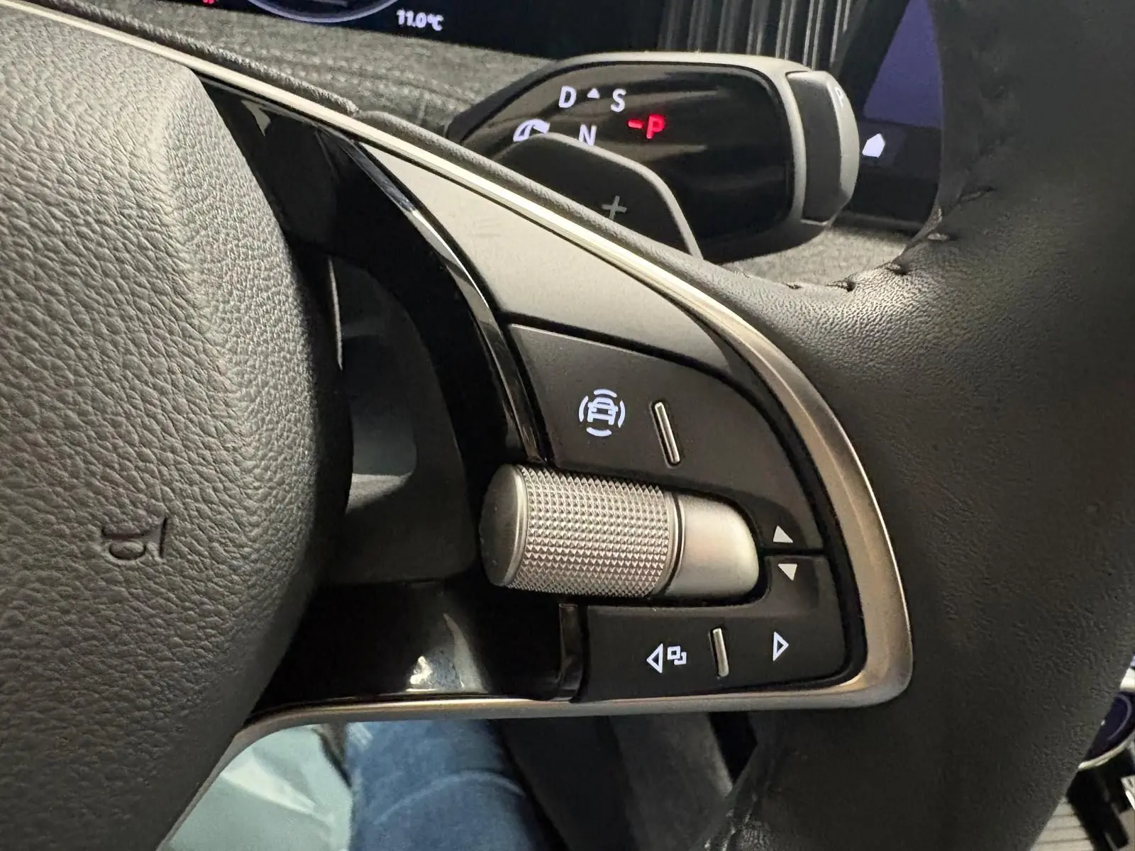 Gros plan sur les commandes à droite du volant en cuir noir du Skoda Superb Combi gris argent 2025, avec molette texturée.