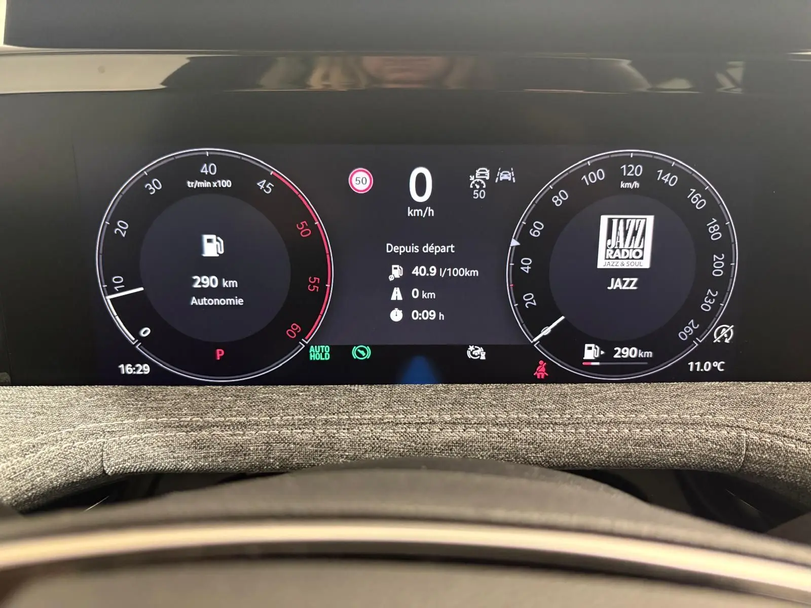 Tableau de bord numérique du Skoda Superb Combi gris argent 2025, affichant vitesse, autonomie et radio Jazz en vue frontale.