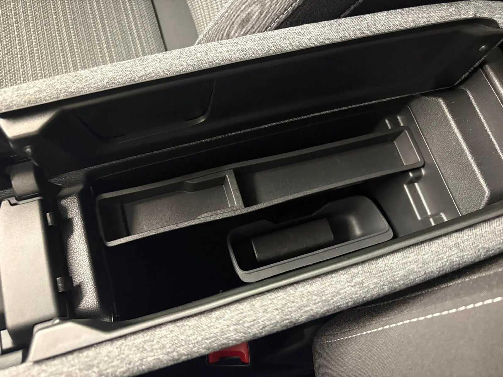 Vue rapprochée de l'accoudoir central ouvert du Skoda Superb Combi gris argent, montrant le rangement intérieur.