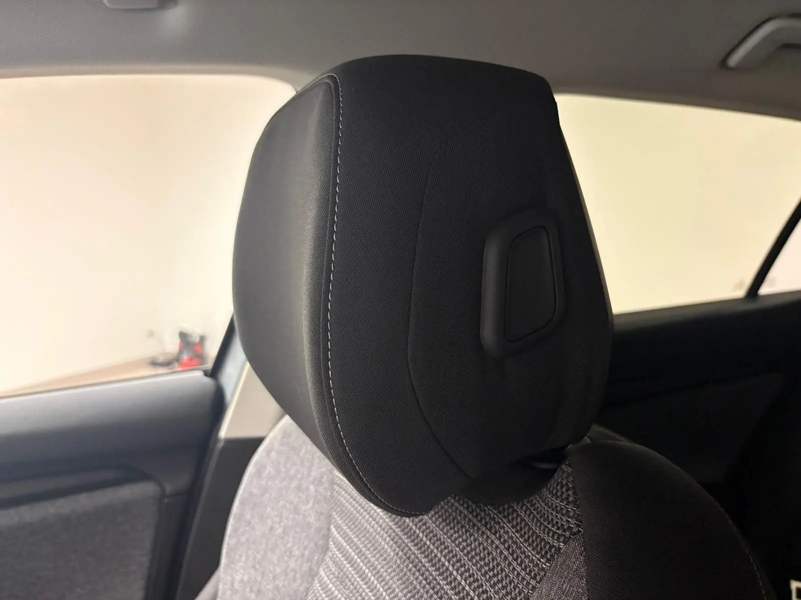 Gros plan sur l'appuie-tête avant gauche en tissu noir et gris du Skoda Superb Combi gris argent 2025.