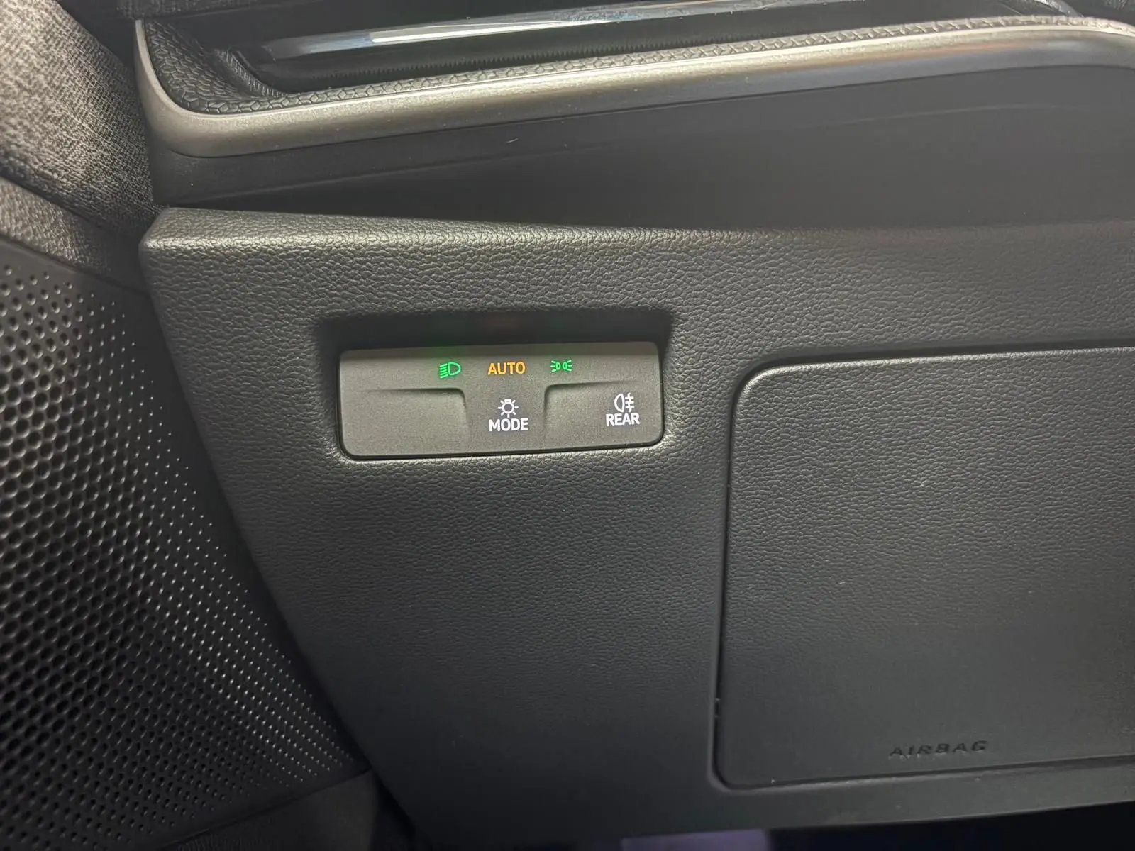 Détail du tableau de bord du Skoda Superb Combi 2025, montrant les commandes d'éclairage automatiques avec indicateurs lumineux verts et orange.