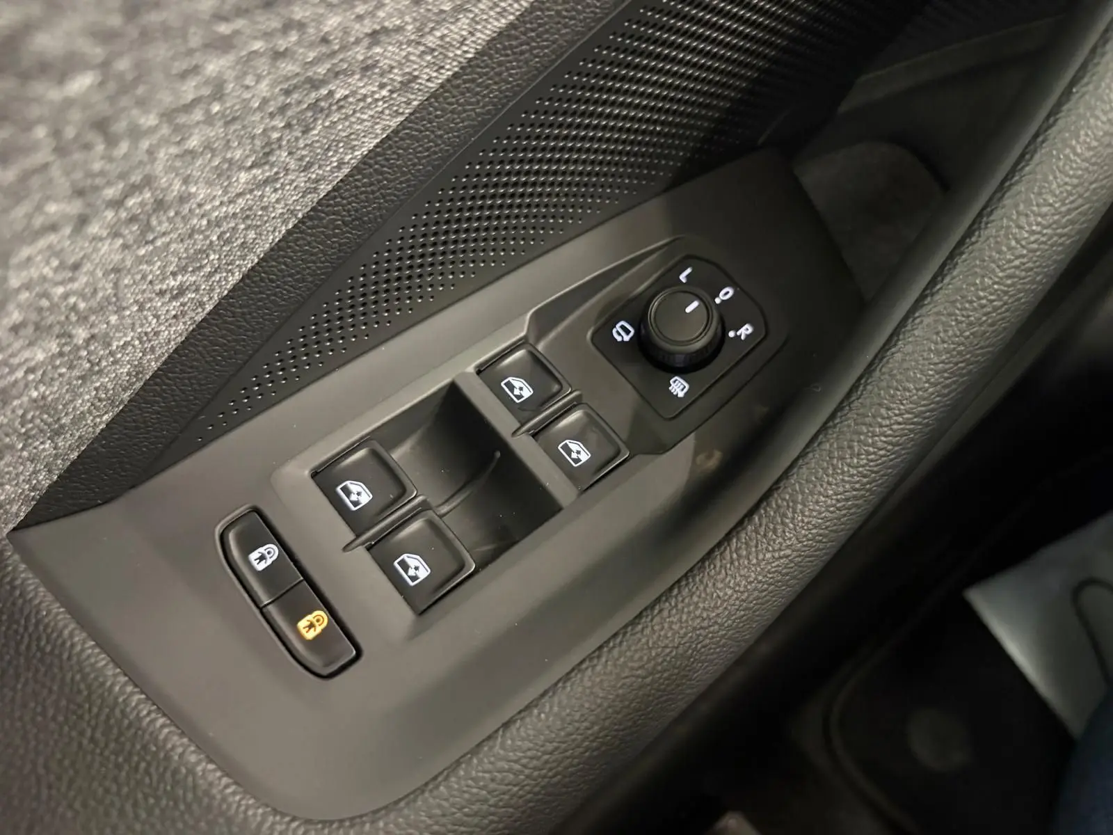 Gros plan sur les commandes des vitres et des rétroviseurs côté conducteur d’un Skoda Superb Combi gris argent 2025.