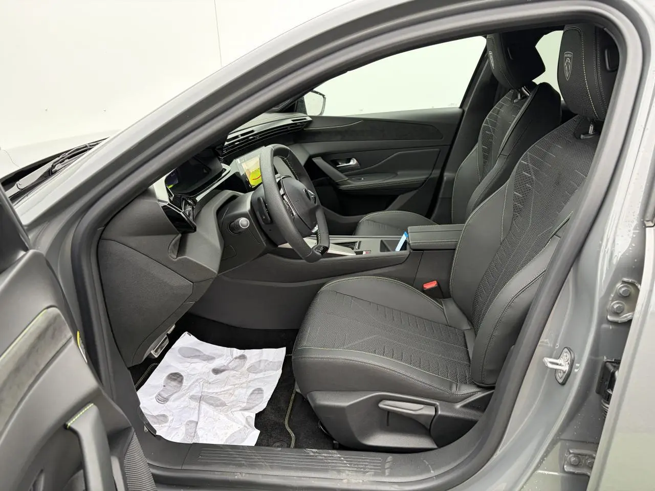 Intérieur côté conducteur de la Peugeot 308 gris selenium, sièges noirs avec surpiqûres vertes et volant compact GT cuir.
