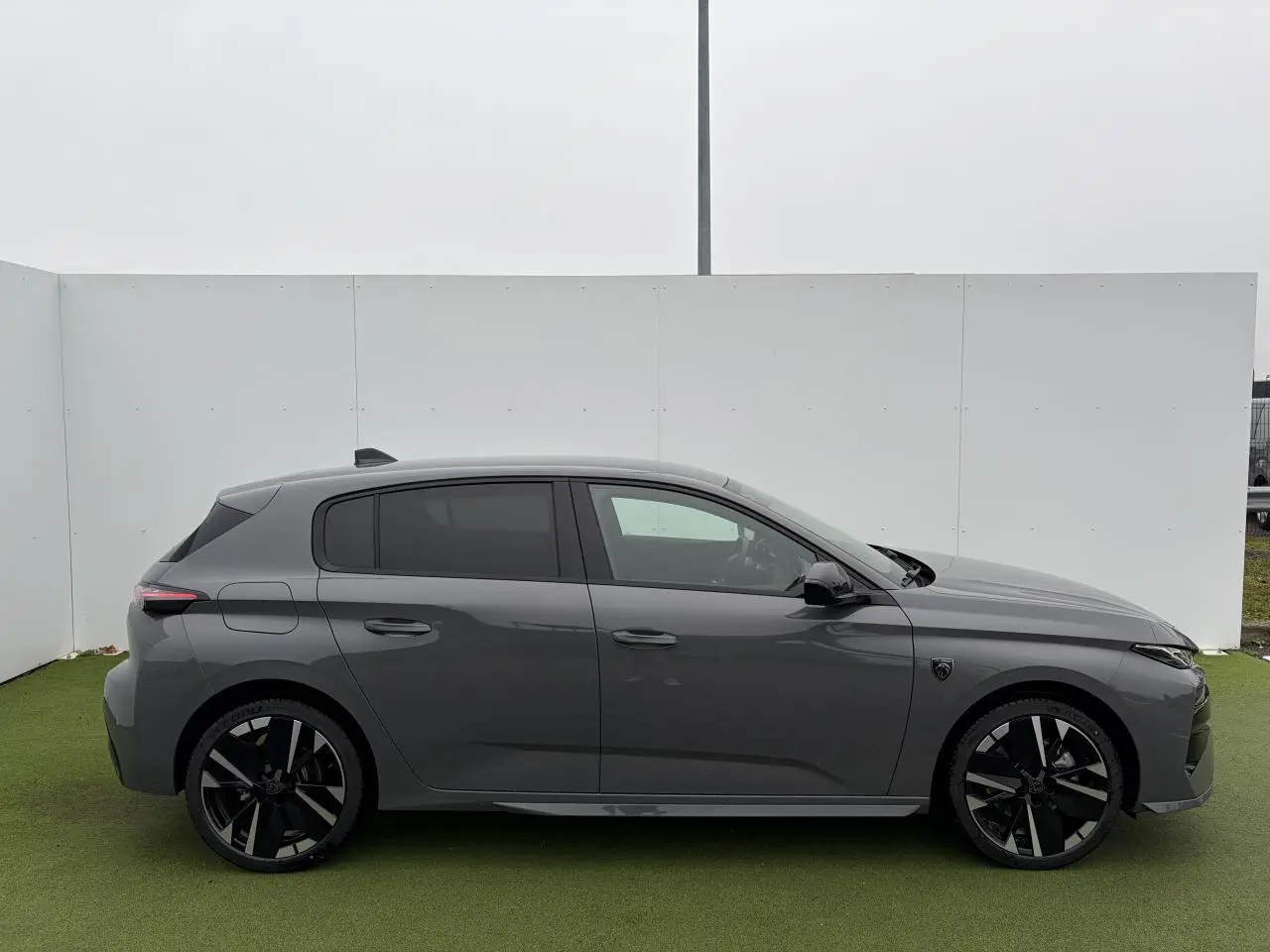 Profil droit d'une Peugeot 308 III gris selenium avec jantes alliage noires et vitres surteintées.