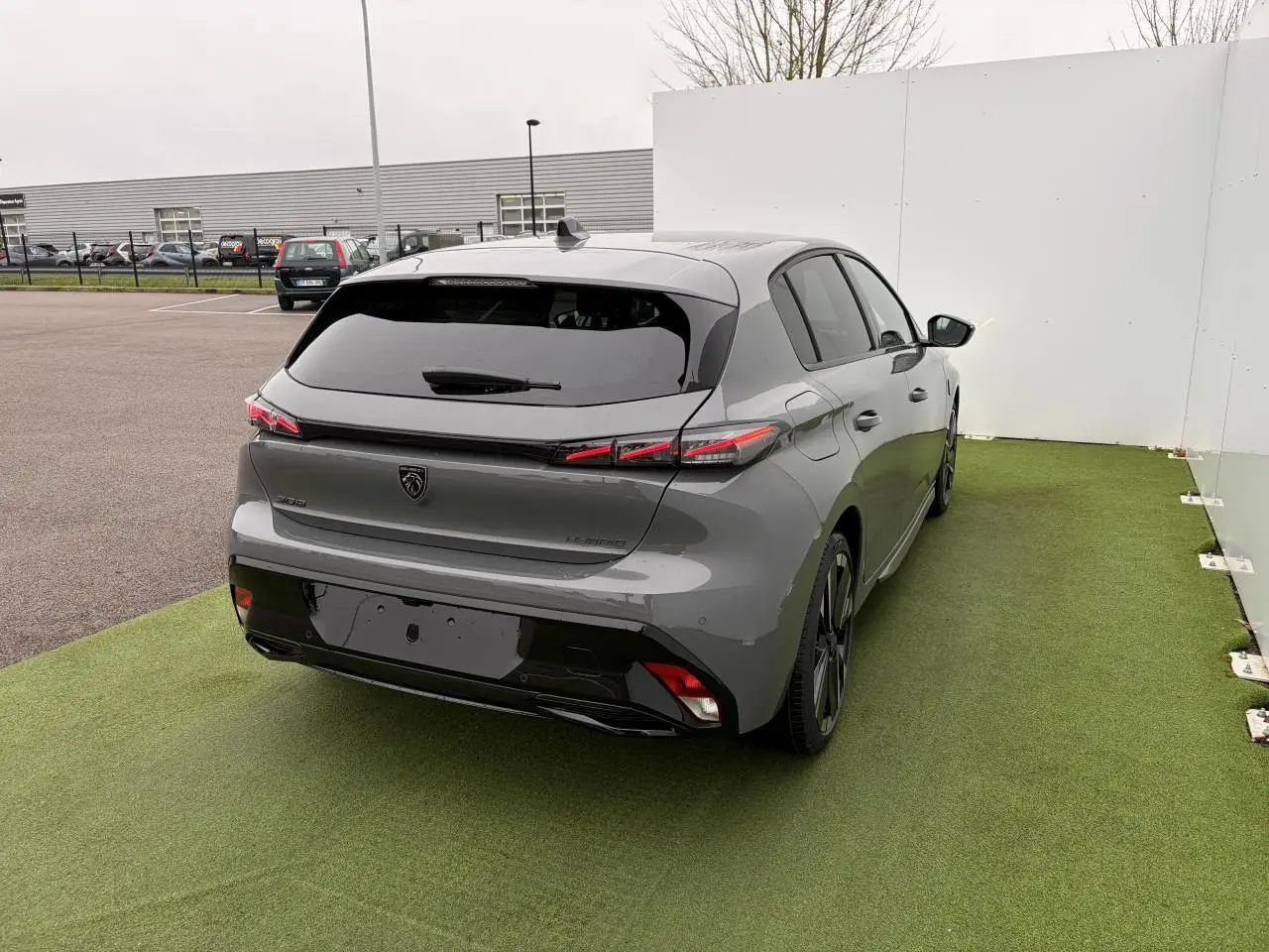 Vue 3/4 arrière droite de la Peugeot 308 III hybride gris selenium avec feux arrière LED et jantes alliage noires.