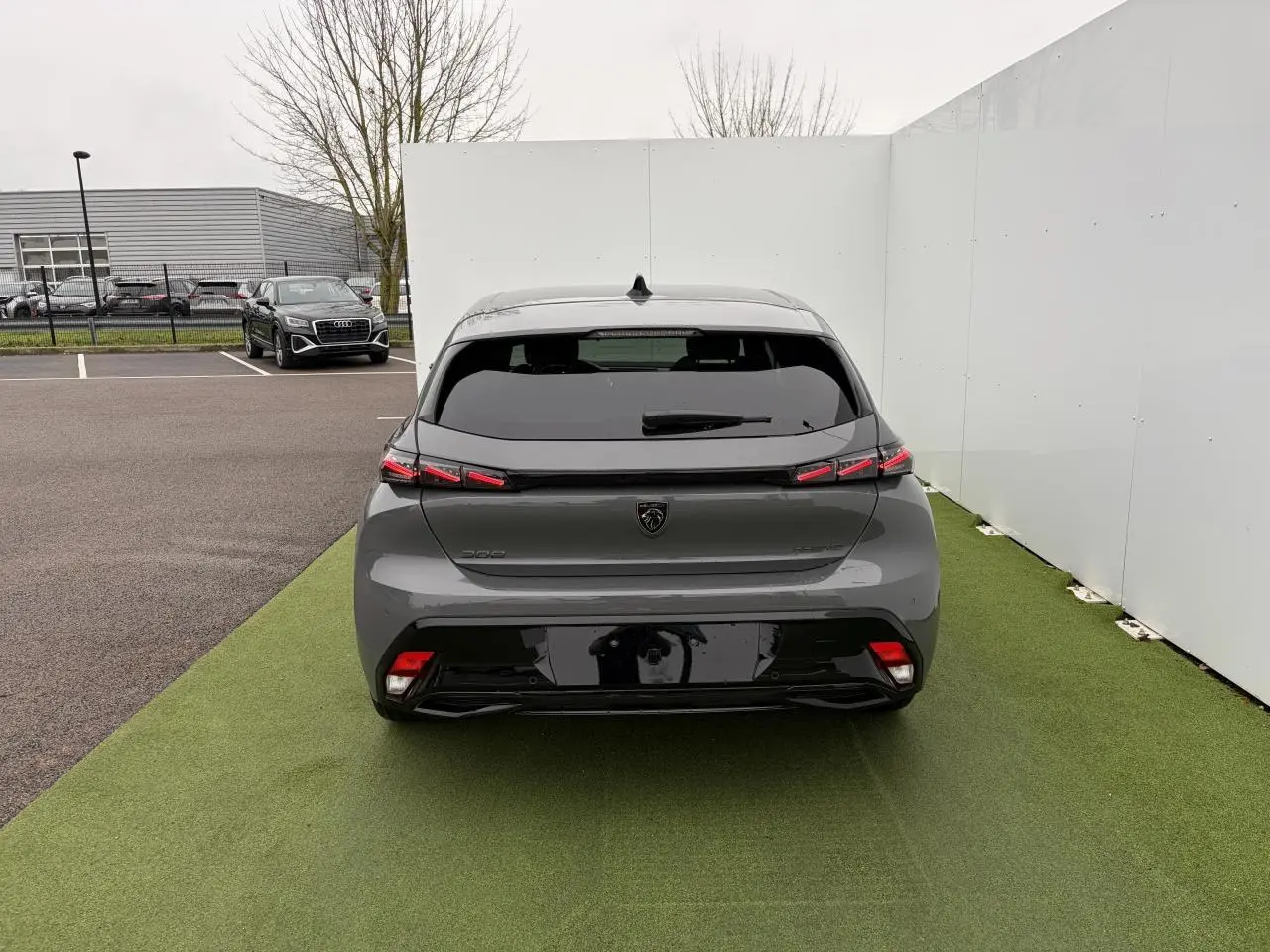Vue arrière d'une Peugeot 308 III gris sélénium avec feux arrière LED en forme de griffes et vitrage surteinté.