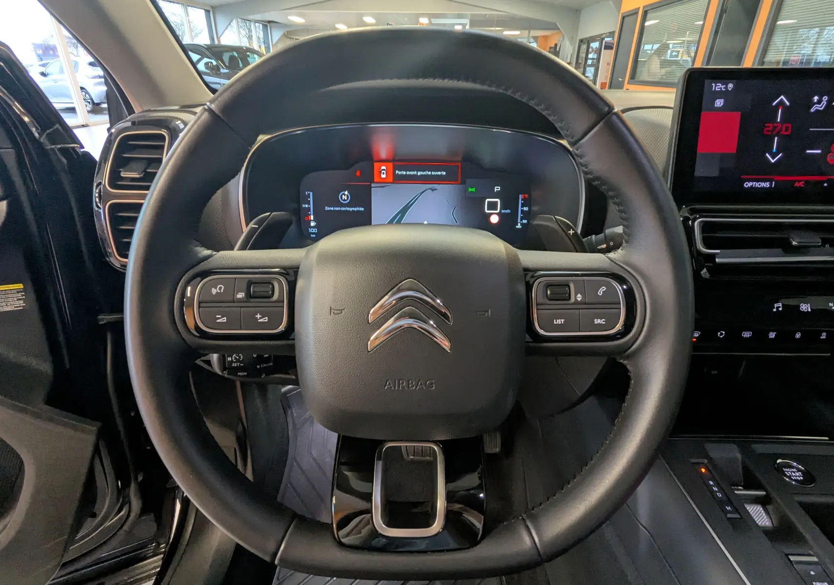 Vue intérieure centrée sur le volant noir en croûte de cuir du Citroën C5 Aircross 2024 avec tableau de bord digital et écran tactile.