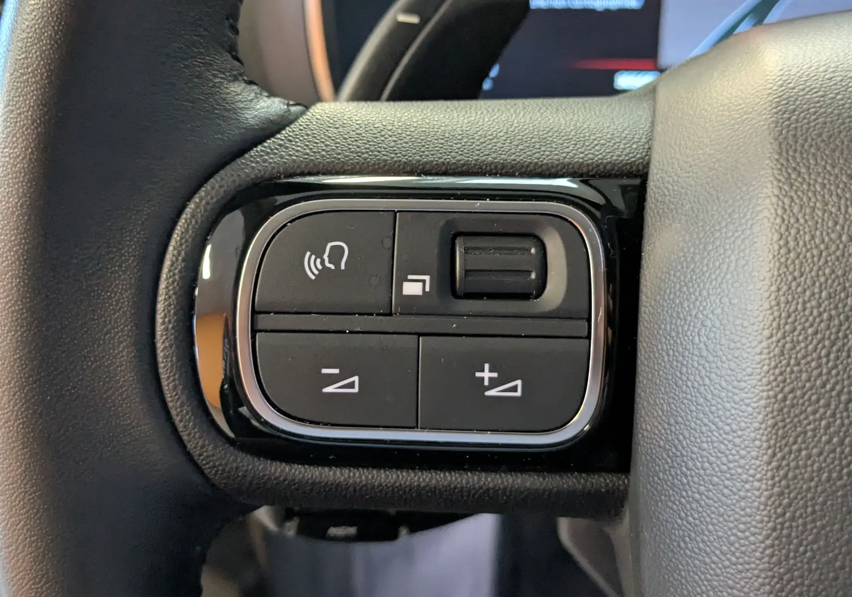 Gros plan sur les commandes de volume et de reconnaissance vocale sur le volant cuir noir du Citroën C5 Aircross 2024.