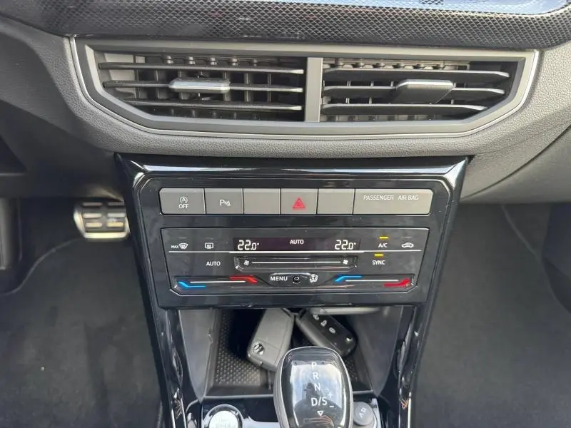 Vue rapprochée de la console centrale du Volkswagen T-Cross 2025 noir nacré, avec commandes climatisation et levier de boîte auto.