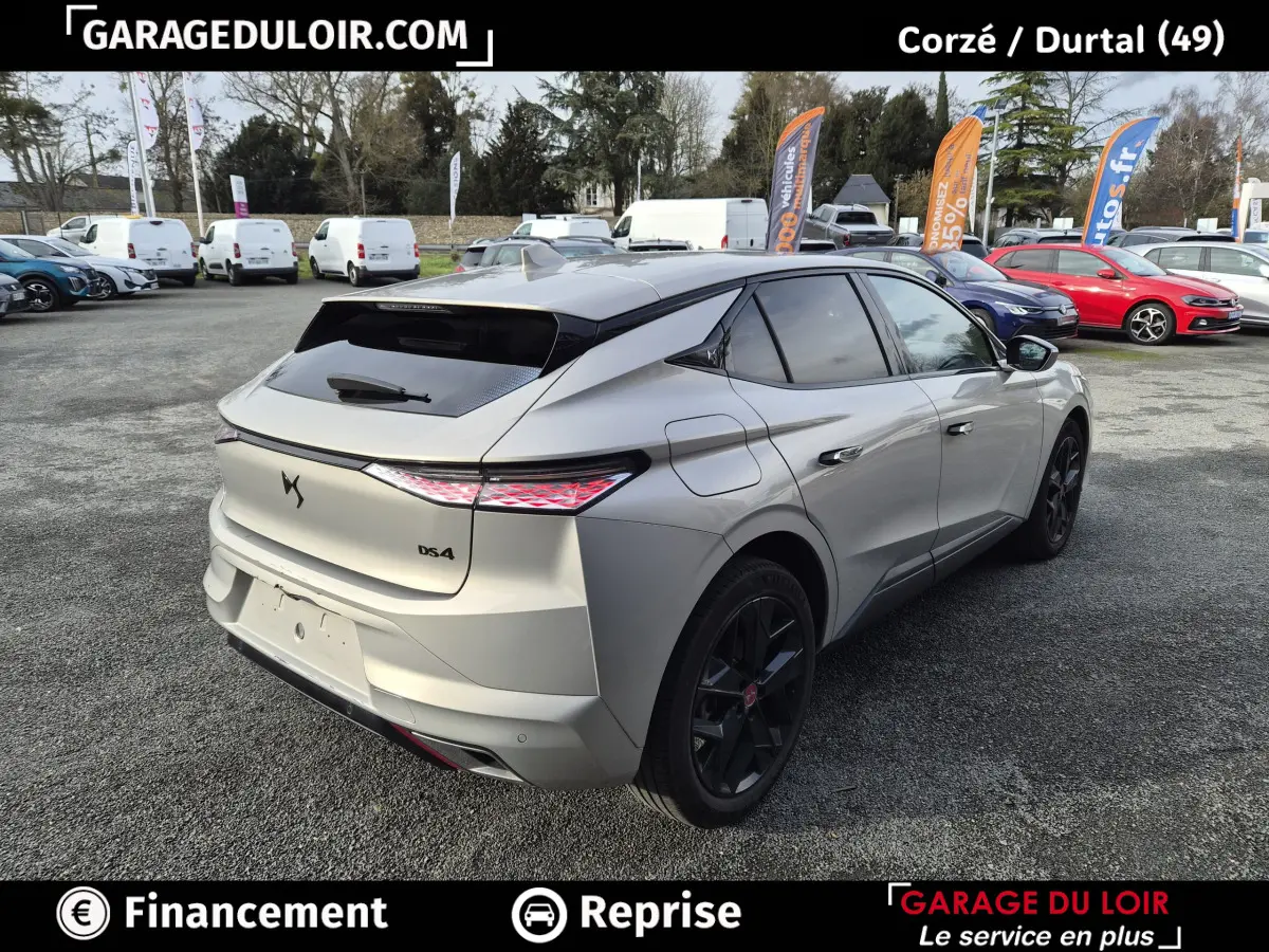 Vue 3/4 arrière droite d'une DS4 beige 2024 avec feux arrière LED et jantes noires sur parking extérieur.