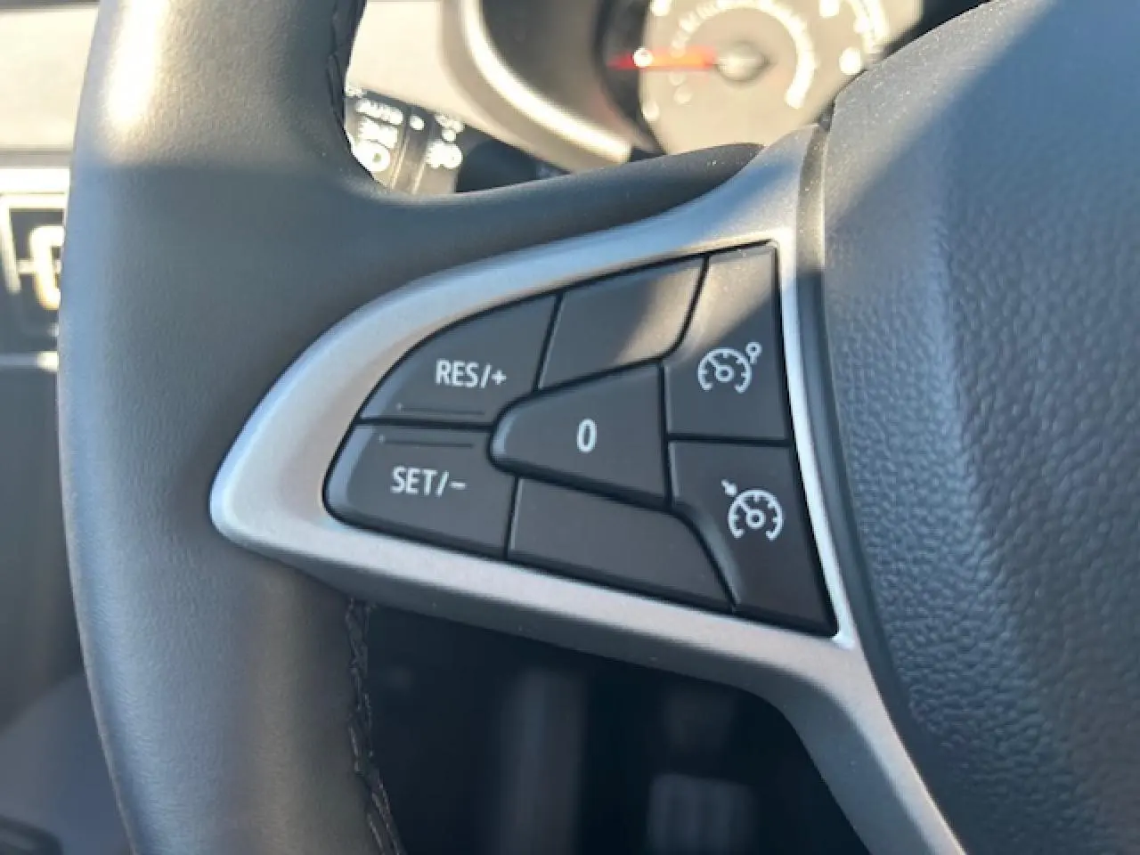 Gros plan sur les commandes de régulateur de vitesse à gauche du volant noir de la Dacia Sandero III Stepway 2025.