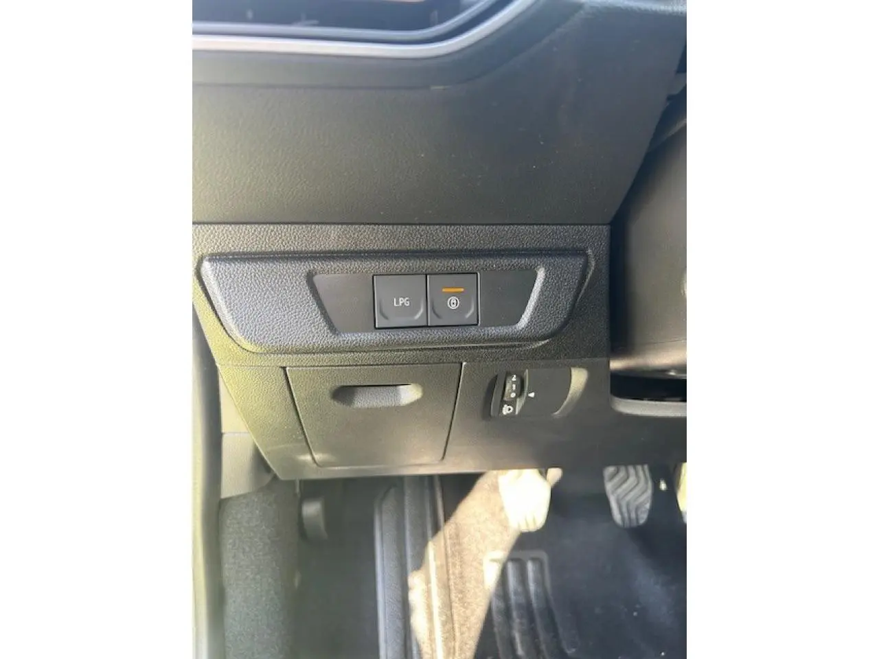 Vue intérieure côté conducteur montrant les commandes LPG et frein à main électrique sur tableau noir.