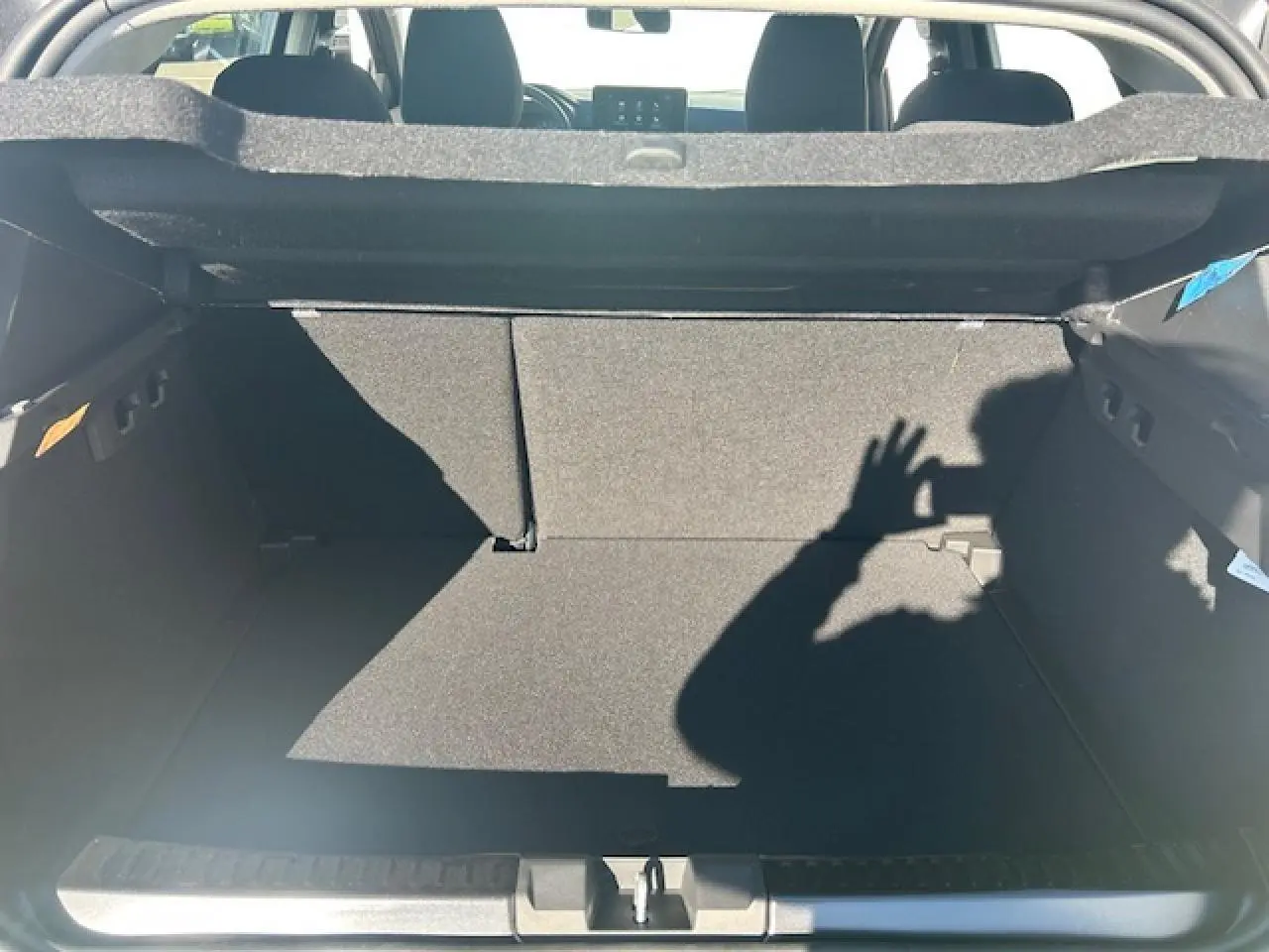 Coffre ouvert vu de l'arrière d'une Dacia Sandero III Stepway noir nacré, intérieur sombre et banquette arrière visible.