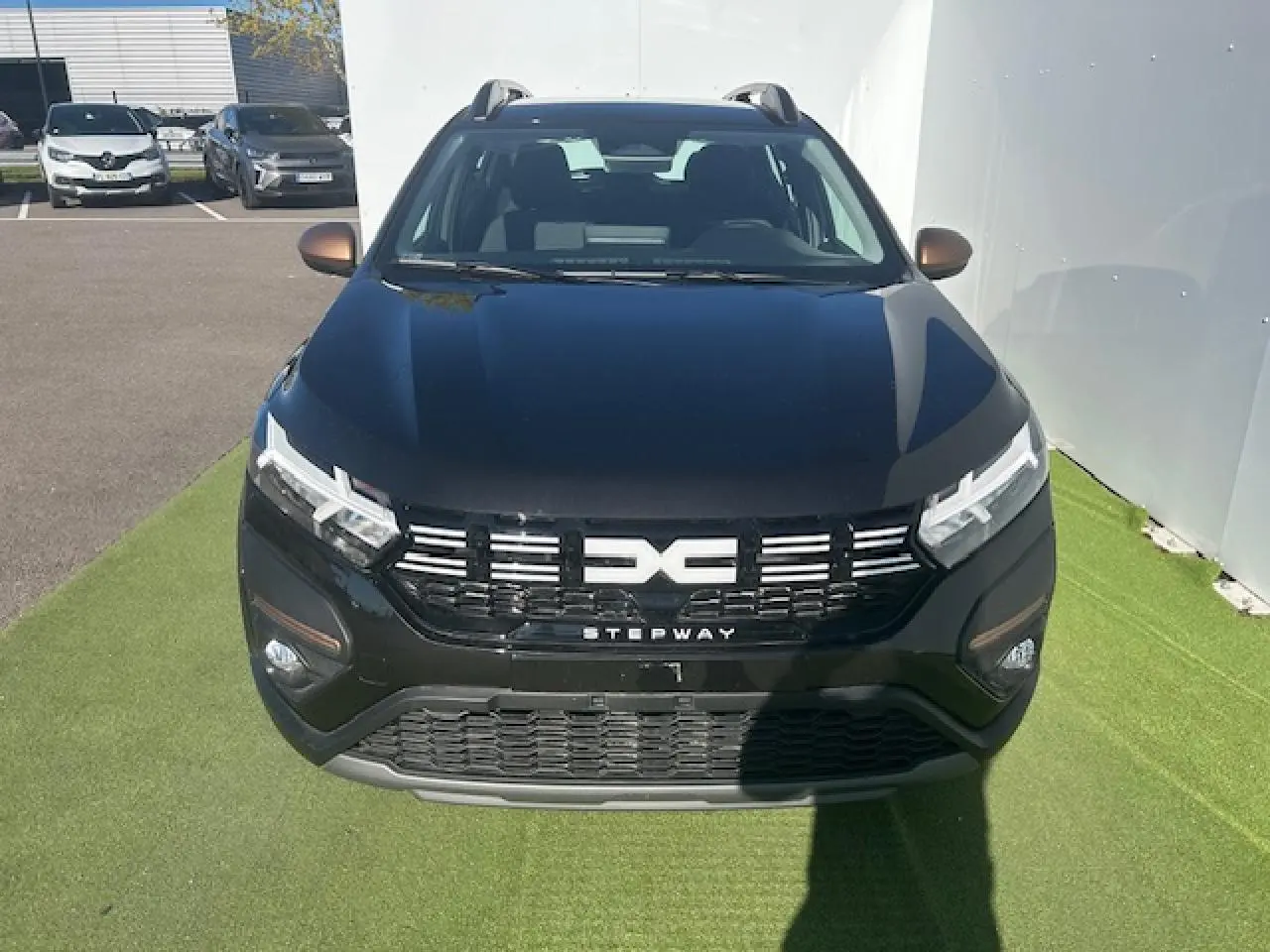 Vue avant d'une Dacia Sandero III Stepway noir nacré avec calandre noire et logo central blanc, sur fond clair.