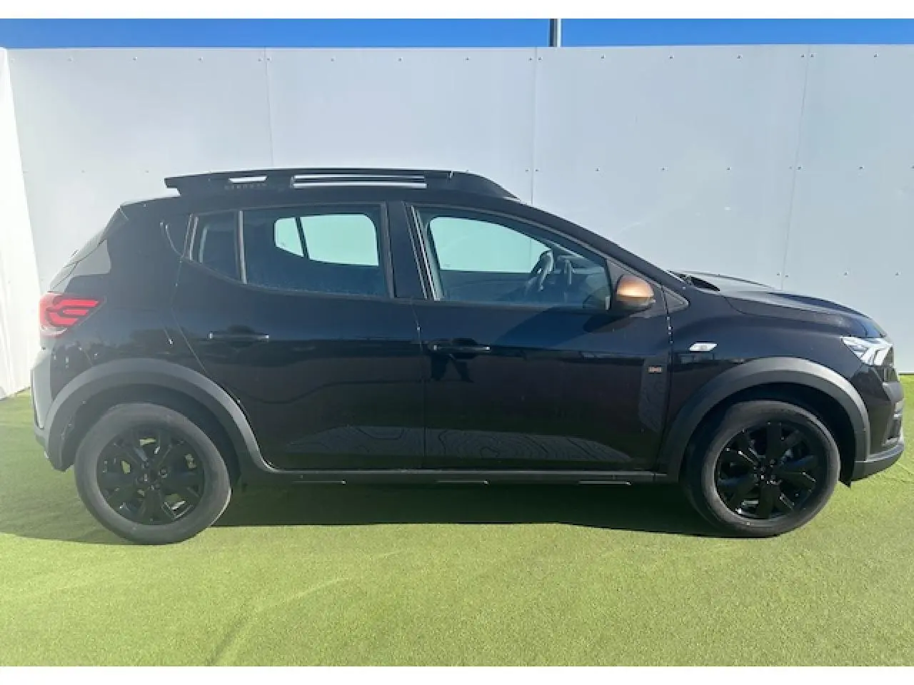 Vue profil droit d'une Dacia Sandero III Stepway noire nacrée avec jantes noires et coques de rétroviseurs brun cuivré.