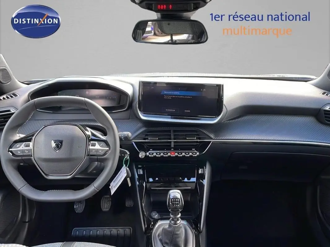 Intérieur Peugeot 2008 gris 2025 vu de face, volant cuir, écran tactile et levier de vitesse manuel visibles.